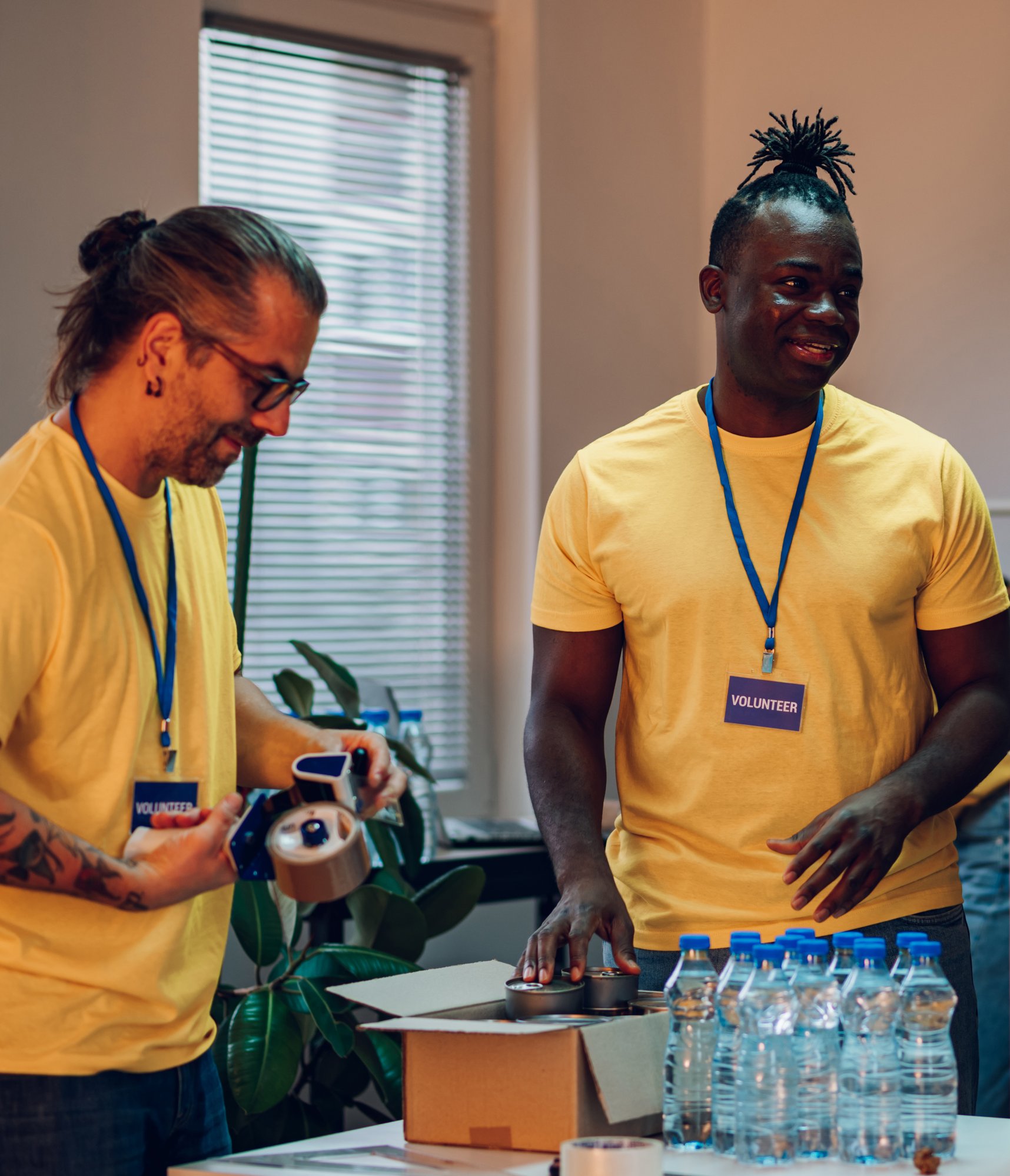 Two people stand over a table with bottled water on it