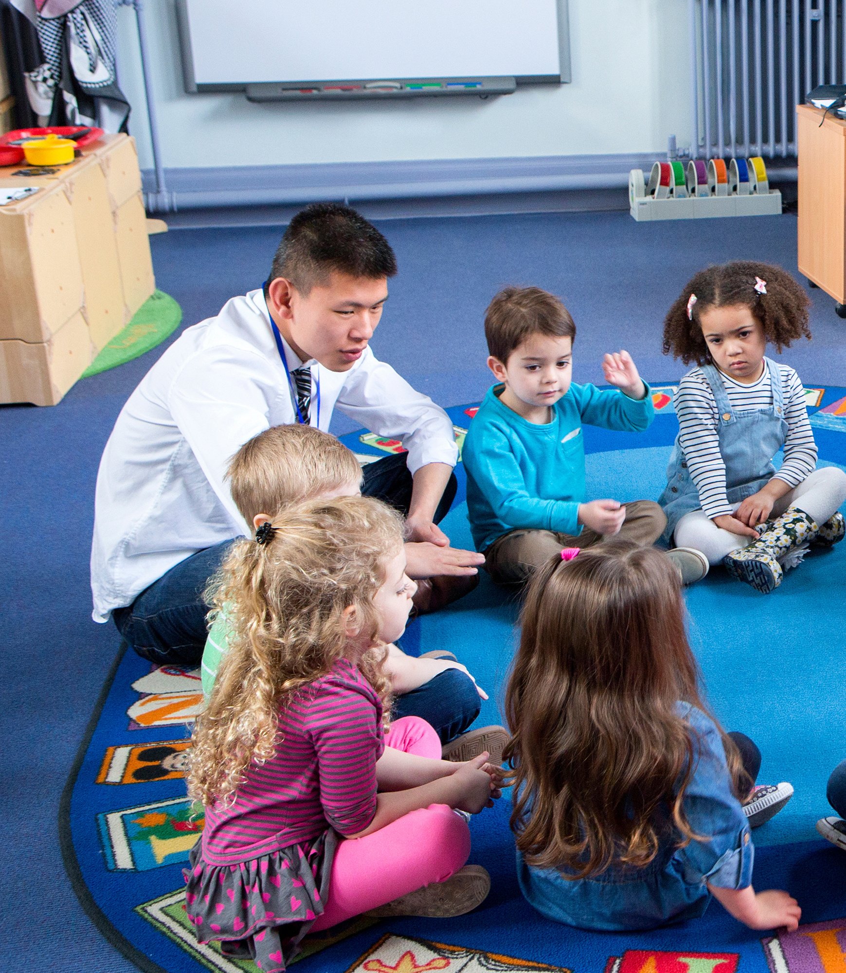 Male teacher with children at Nursery school Story Time
