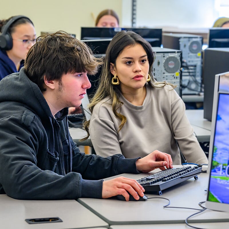 Two students working together in class on the computer